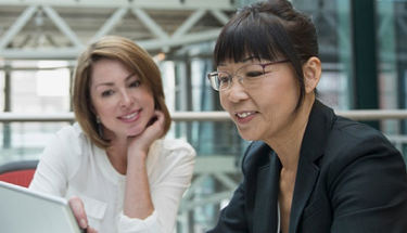 Two businesswomen discussing information on a computer