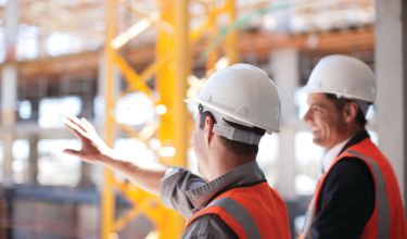 Two people wearing hardhats and chatting