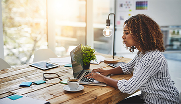 A businesswoman sitting at a desk working on a laptop